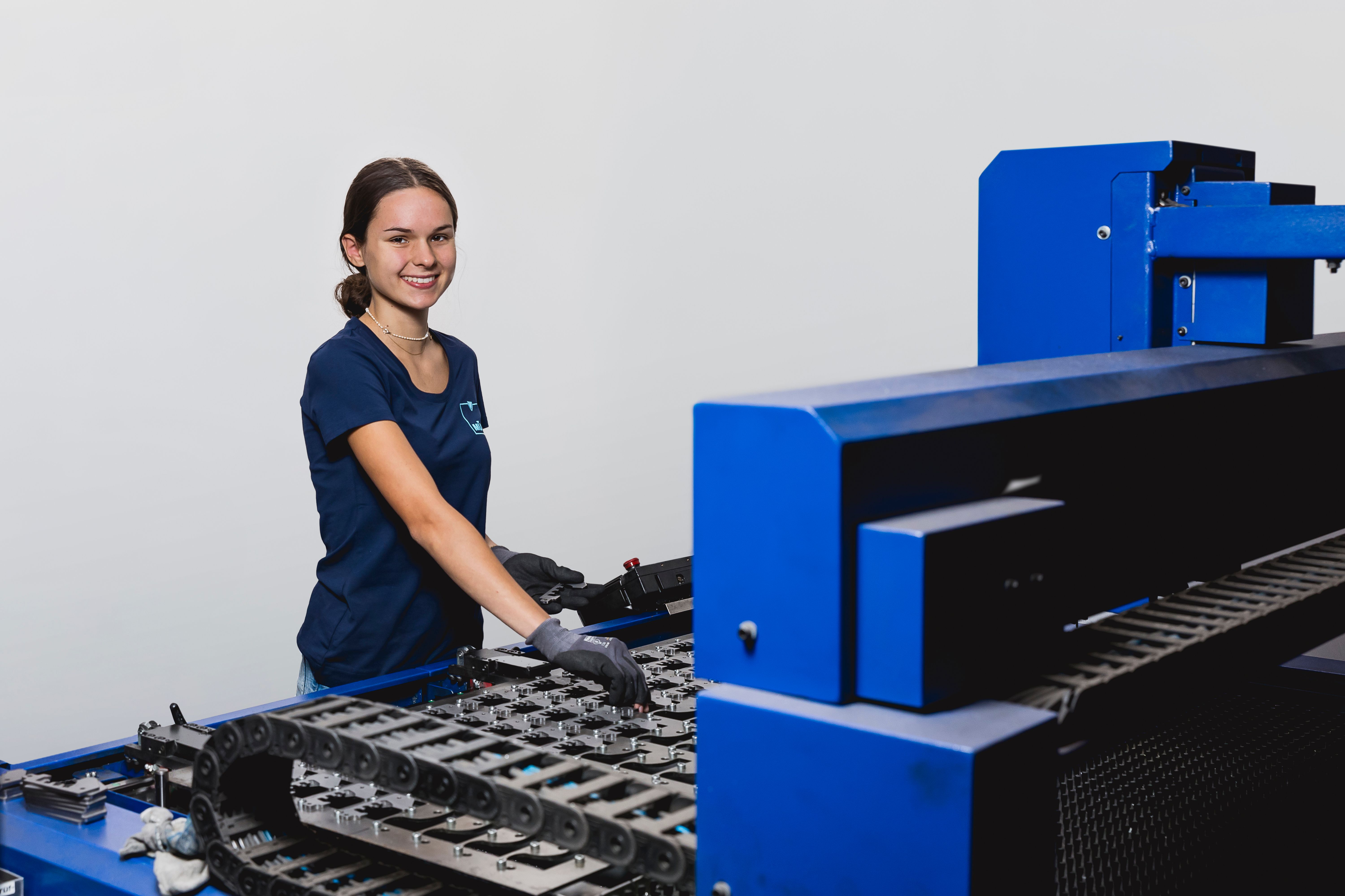 Junge Mitarbeiterin an Maschine